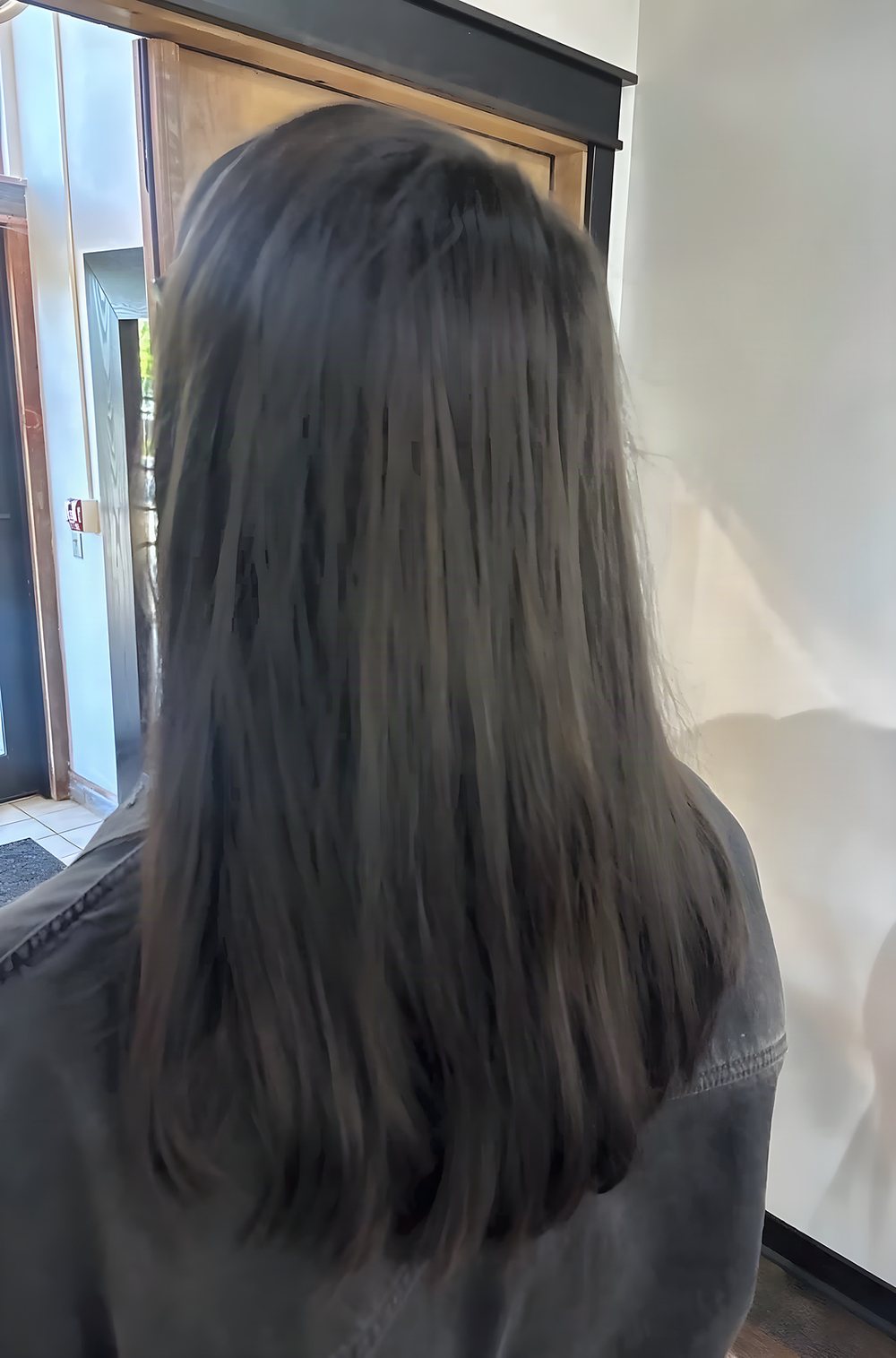 Back view of Priscilla's guest: deep brunette, straight, cut shorter.